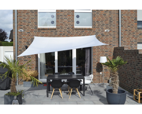 Terrasse mit Sonnensegel, Tisch und Stühlen vor einem Haus