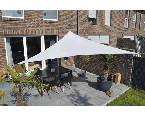 Terrasse mit dreieckigem Sonnensegel, Tisch und Stühlen vor einem Backsteinhaus