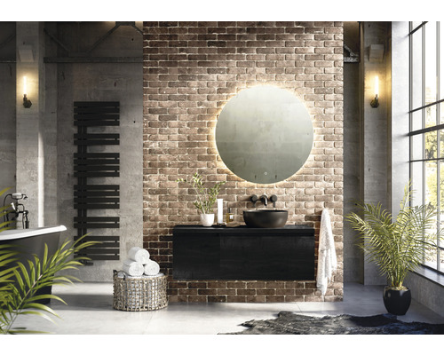 Modernes Badezimmer mit freistehender Badewanne, Handtuchwärmer, Waschtischunterschrank, runder Spiegel mit Beleuchtung und Ziegelwand