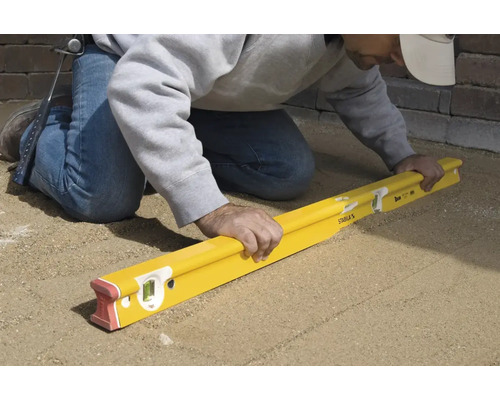 Handwerker verwendet Wasserwaage zum Nivellieren von Pflastersteinen