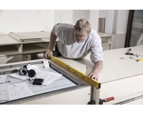 Handwerker prüft Werkstück mit Wasserwaage auf Werkbank