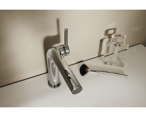 Mitigeur de lavabo brillant à côté d''un pinceau de maquillage et d''un flacon de parfum sur un lavabo