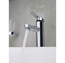 Mitigeur de lavabo chromé avec jet d''eau et étagère en verre dans la salle de bain.