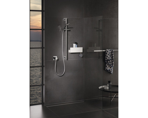 Salle de bain moderne avec douche, barre de douche et espace de rangement pour les accessoires de douche.
