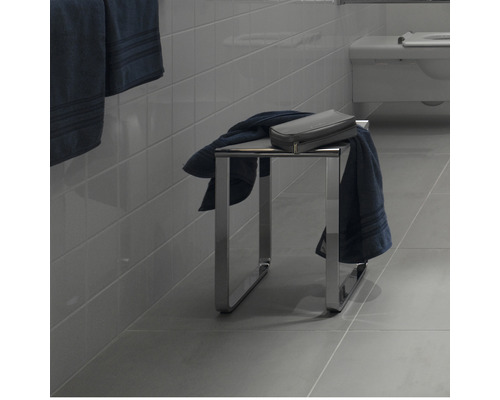 Badezimmer mit einem Hocker aus Metall, Handtüchern und einem Kulturbeutel