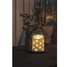 Bougie LED décorative à motifs à points sur une table, à côté d''un vase avec des branches.
