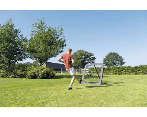 Junge schéisst Fussball an en tragbare Fussballgol am Gaart.