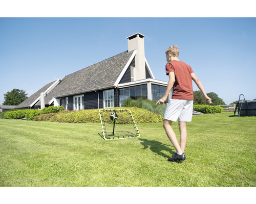 Junge spielt mit Fußballtor im Garten vor einem Wohnhaus