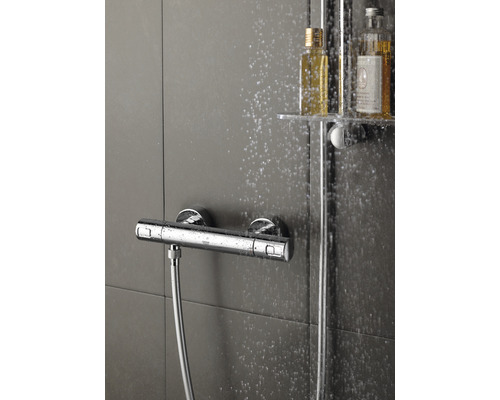Robinet de douche apparent avec flexible de douche et flacons de shampoing dans la douche
