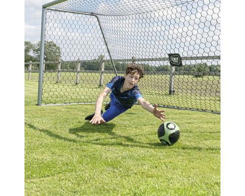 Junge hält einen Fußball vor einem Fußballtor.