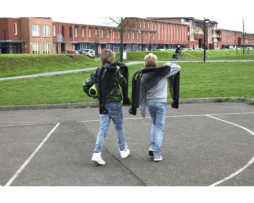 Zwei Kinder tragen zusammengeklappte Bollerwagen auf einem Schulhof.