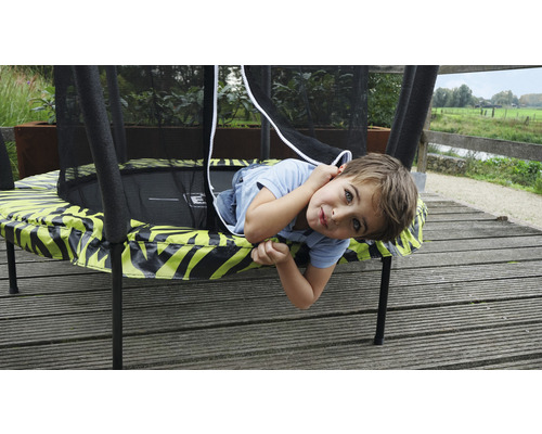 Enfant allongé sur un trampoline de jardin avec filet de sécurité