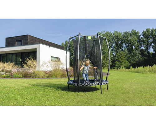 Enfant sautant sur un trampoline de jardin avec filet de sécurité dans le jardin