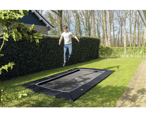 Ebenerdiges Gartentrampolin mit springendem Mann im Garten