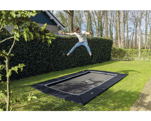 Eingebautes Gartentrampolin mit springendem Jungen im Garten.