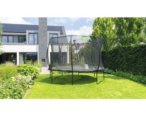 Trampolin mit Sicherheitsnetz im Garten mit springendem Kind
