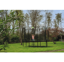 Enfant sur un trampoline de jardin avec filet de sécurité et échelle