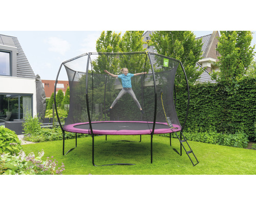Fille sautant sur un trampoline de jardin avec filet de sécurité et échelle