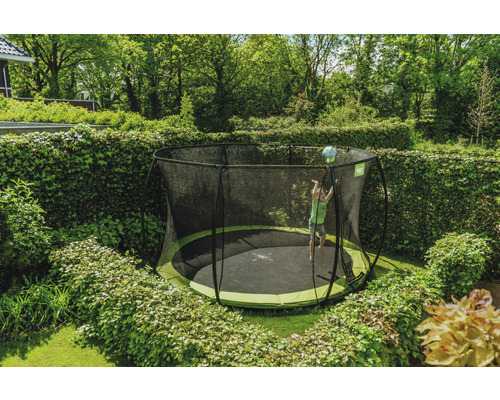 Scène de jardin avec un enfant sur un trampoline de jardin rond avec filet de sécurité.