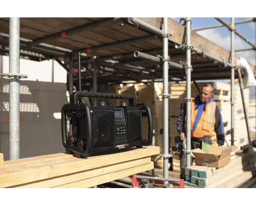 Radio de chantier sur une surface en bois avec un ouvrier du bâtiment en arrière-plan