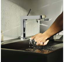 Une personne se lave les mains sous un robinet chromé dans un lavabo de salle de bains