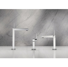 Trois robinets de lavabo modernes en métal devant un mur de marbre.