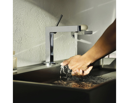 Une personne se lave les mains sous un robinet chromé dans un lavabo.