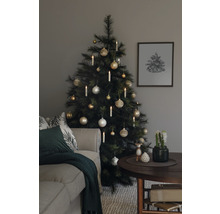 Sapin de Noël décoré avec des boules et des bougies à côté d''un canapé et d''une table