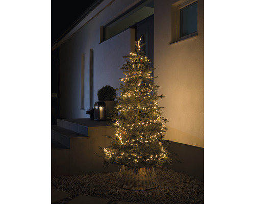 Sapin de Noël avec guirlande lumineuse devant une maison