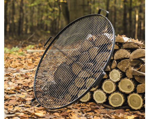 Grille de barbecue ronde en métal avec pile de bois à l''extérieur
