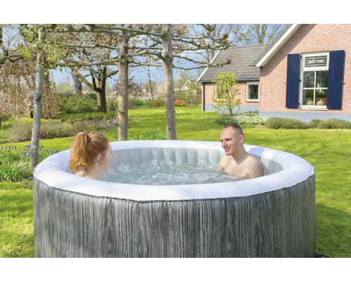 Bain à remous gonflable avec deux personnes dans le jardin