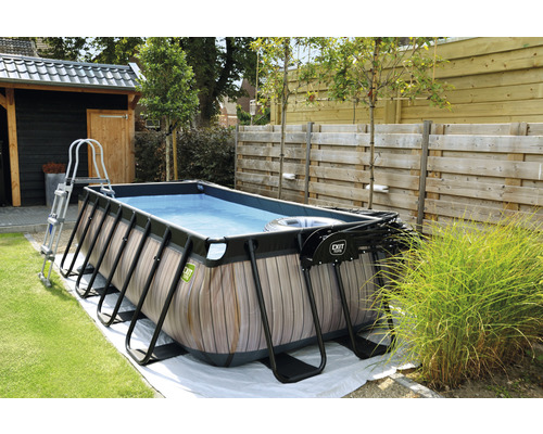 Piscine rectangulaire avec aspect bois, échelle et pompe de filtration dans le jardin