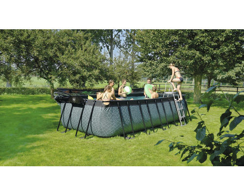 Piscine rectangulaire avec des personnes et une échelle dans le jardin
