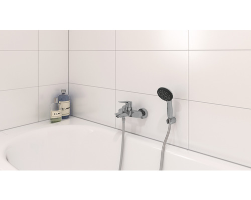 Salle de bains avec baignoire, robinet et douchette, ainsi que savon et shampoing