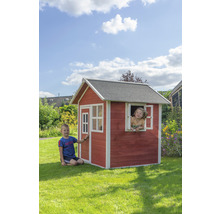 Des enfants jouent dans une cabane en bois avec une porte et des fenêtres dans le jardin.