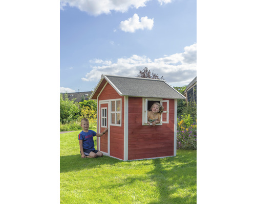 Kinder spielen in einem Holzspielhaus mit Tür und Fenster im Garten.