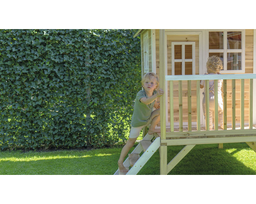 Kinder spielen in einem hölzernen Spielhaus im Garten.