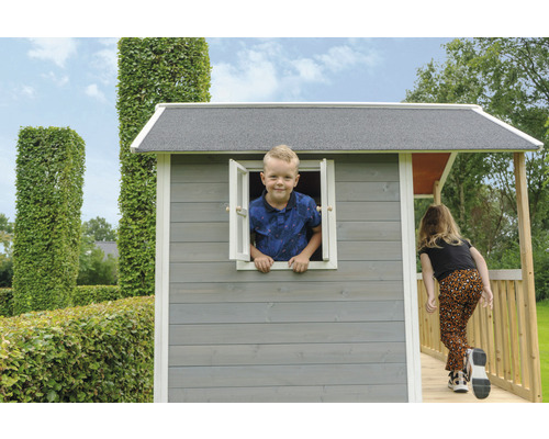 Des enfants jouent dans une cabane en bois grise avec une rampe