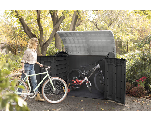 Fahrradbox aus Kunststoff mit Fahrrädern und einer Frau im Garten