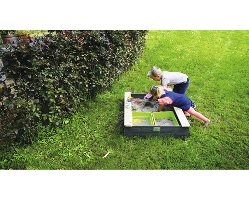Zwei Kinder spielen in einem Sandkasten im Garten.