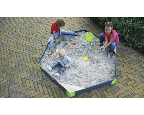 Des enfants jouent dans un bac à sable hexagonal avec des jouets de sable