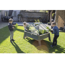 Des enfants plantent un potager surélevé avec un châssis dans le jardin.
