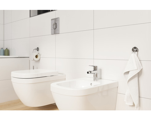 Salle de bain lumineuse avec toilettes, bidet et carreaux muraux blancs