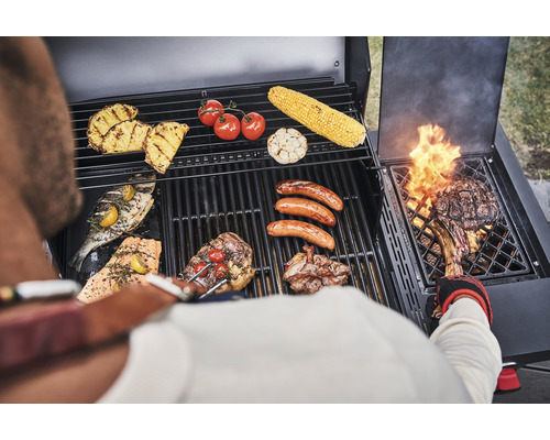 Grillszene mit Fleisch, Fisch, Gemüse und Obst auf einem Grill zubereitet