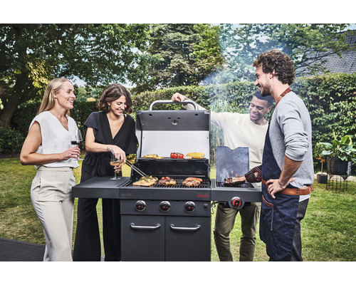 Gruppe von Personen grillt im Garten mit einem Gasgrill.