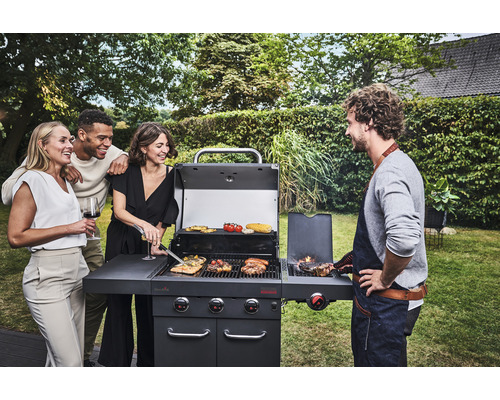 Gruppe von Menschen grillt auf einem Gasgrill im Garten.