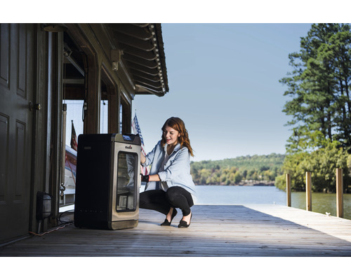 Femme utilisant un fumoir à l''extérieur près d''un plan d''eau