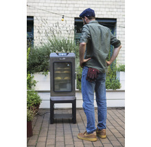 Un homme regarde un fumoir électrique dans le jardin.