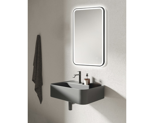 Salle de bains moderne avec lavabo, robinet, miroir éclairé et serviette