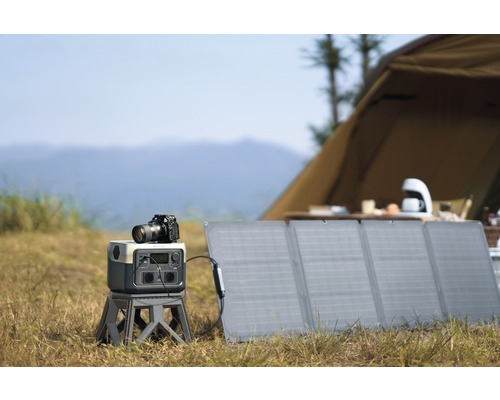 Scène de photographie en extérieur avec panneau solaire, générateur électrique et appareil photo devant une tente